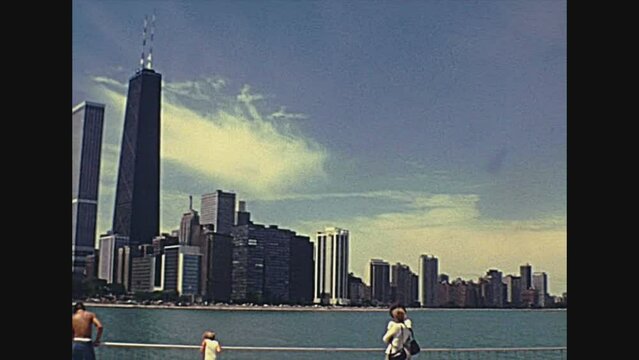 Chicago, Lake Michigan, Illinois, United States - Circa 1977: people on vacation in Milton Lee Olive Park, waterfront skyline of Chicago. Vintage dress 70s. Historical United States of America.