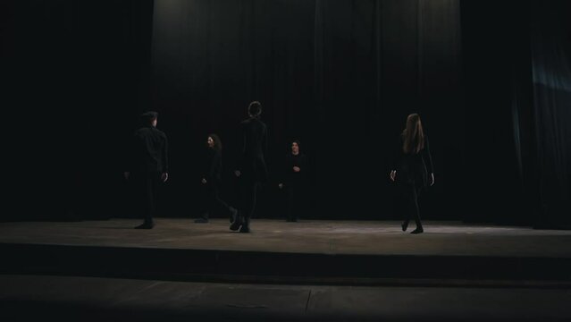 Side view of five confident student actors in the theater walking on stage during their rehearsal and preparation for classes at the theater university