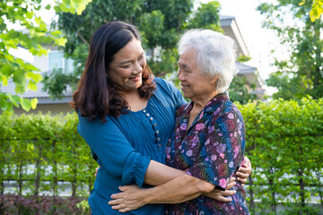 Asian elderly woman hug with her daughter with love, care, help, encourage and empathy at park, healthy strong medical concept.