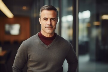 Naklejka premium Portrait of a blissful man in his 40s wearing a cozy sweater in front of sophisticated corporate office background