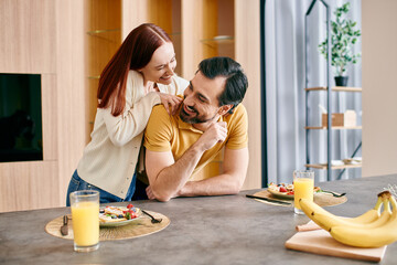 A beautiful redhead woman and a bearded man enjoying a peaceful breakfast together in their modern...
