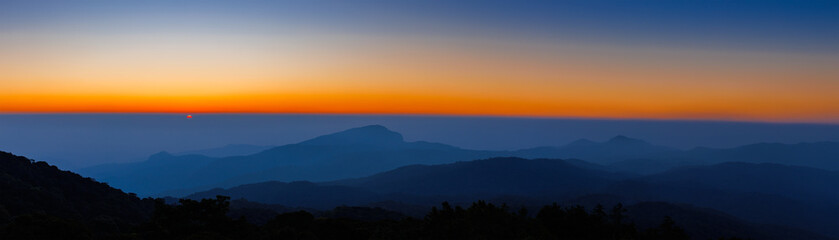 amazing dramatic cloudscape in sunset with sun rays over misty blue mountains landscape  