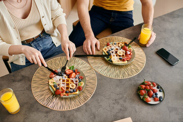 A beautiful adult couple spending quality time together while eating breakfast at a table in a modern apartment.