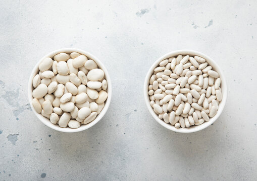 Two bowl plates with large and medium raw beans on kitchen table.Macro.