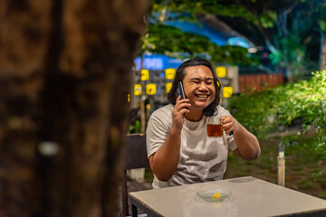 Young Asian man, digital nomad working remotely from cafe, using laptop and smartphone. young Asian...