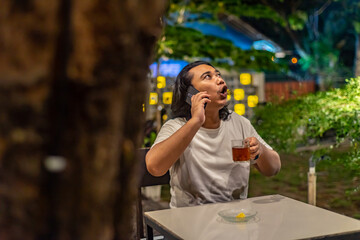 Young Asian man, digital nomad working remotely from cafe, using laptop and smartphone. young Asian...