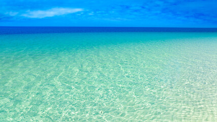 View of sandy beach for summer vacation concept. Nature of the beach and sea in summer with sunlight, and light sand. The sea sparkles against the blue sky. Sandy Beach for summer vacation concept