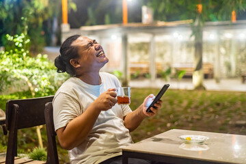 Young Asian man, digital nomad working remotely from cafe, using laptop and smartphone. young Asian...