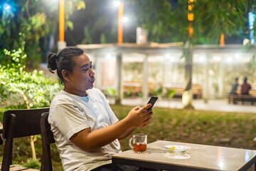 Young Asian man, digital nomad working remotely from cafe, using laptop and smartphone. young Asian...