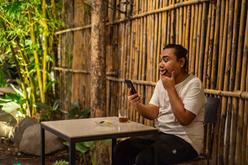 Young Asian man, digital nomad working remotely from cafe, using laptop and smartphone. young Asian...