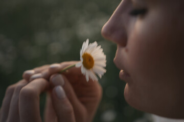 A woman is holding a white flower and smelling it. Concept of calm and serenity, as the woman takes...
