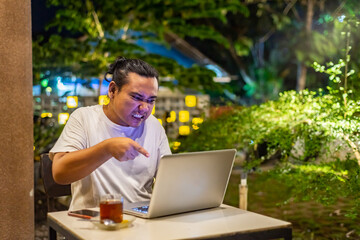 Young Asian man, digital nomad working remotely from cafe, using laptop and smartphone. young Asian...