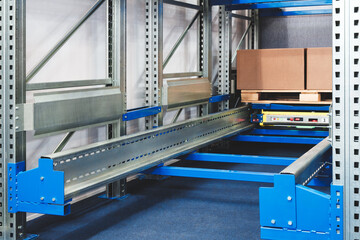 A blue and silver rack with a yellow box on it. The box is on a conveyor belt