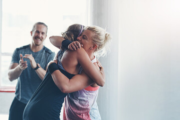 Celebration, gym and women with hug, fitness and clapping of success, athlete or victory in club for sports. Congratulations, happy and applause for exercise, practice and people together for workout