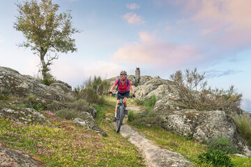 active senior woman cycling with her electric mountain bike in the rough landscape of National Parc Serra de São Mamede near Marvao in central Portugal, Europe
