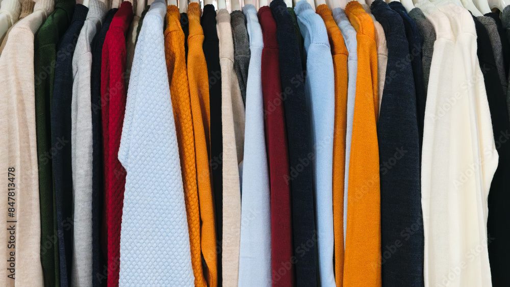 Aufkleber a row of sweaters hanging on a rack, with some in bright colors and others in more muted tones