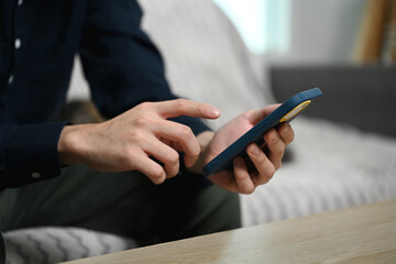 Fototapeta premium Cropped shot of young man relaxing on a couch at home and using mobile phone