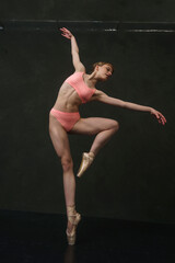 young ballerina in lingerie with a muscular body makes ballet steps demonstrating stretching and eversion