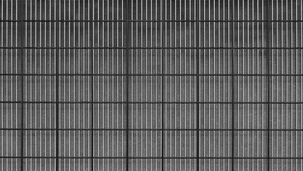 A black and white photo of a wall with a grid pattern. The photo has a moody and somewhat eerie feel to it