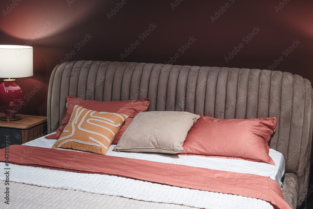 Poster a bed with a red comforter and pillows. the pillows are arranged in a way that creates a sense of co