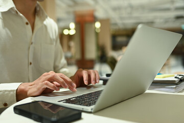 Cropped shot male employee working on his laptop at modern coworking space