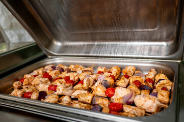 Close-up view of seasoned chicken and vegetables on a baking tray inside an oven, ready for cooking