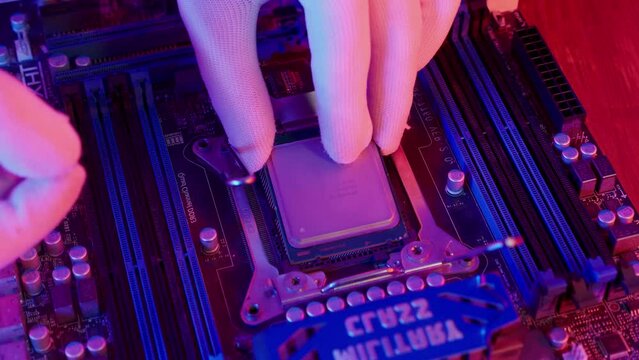 Technician laying CPU into the motherboard socket Computer service and upgrade concept. Processor close up in neon light