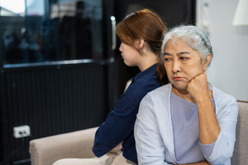 Granddaughter and her grandmother sitting on the sofa, angry at each other, their backs to each other.