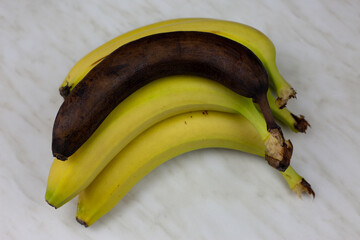 Ugly rotten banana lies on fresh banana fruits