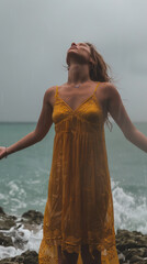 Woman Embracing Rain by the Ocean in Yellow Dress, Experiencing the Beauty of Nature, Joyous Moment, Powerful Connection with Nature on a Rainy Day at the Seaside