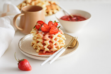 Belgian waffles with strawberries and fresh jam on white table. Summer food concept. Soft focus