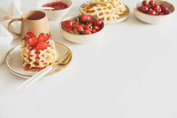 Breakfast with Belgian waffles, strawberries and fresh jam on white table. Summer food concept. Top view. Copy space