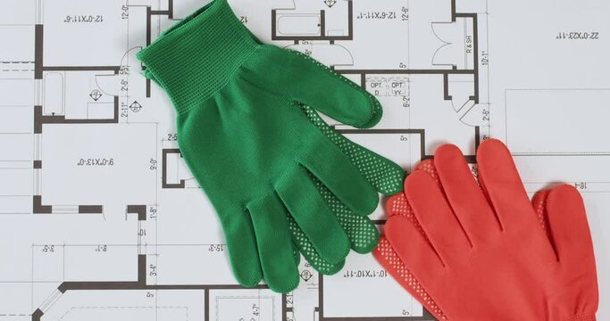 Throwing of work gloves on residential building floor plan view from above. Worker hands protection falls on house blueprint at construction site