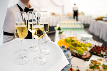 Close-up of champagne glasses on a serving tray at a catering event, with a blurred background