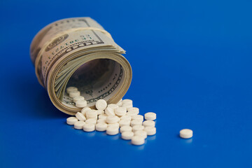 A rolled-up stack of hundred-dollar bills with white pills spilling out, money for medication.