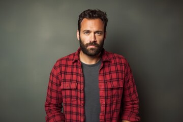 Obraz premium Portrait of a glad man in his 30s wearing a comfy flannel shirt in minimalist or empty room background