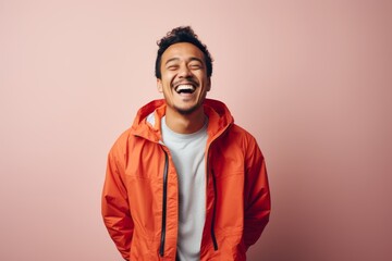 Obraz premium Portrait of a cheerful man in his 30s wearing a functional windbreaker in front of minimalist or empty room background