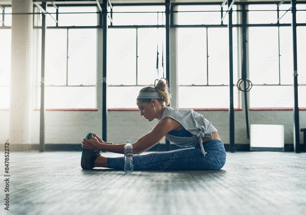 Wall mural Exercise, legs and stretching with woman on floor of gym for health, improvement or wellness. Fitness, training and warm up for workout with athlete getting ready for physical improvement routine