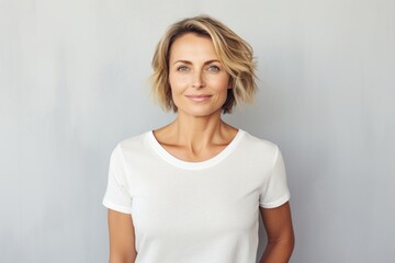 Portrait of a blissful woman in her 40s dressed in a casual t-shirt isolated in minimalist or empty room background