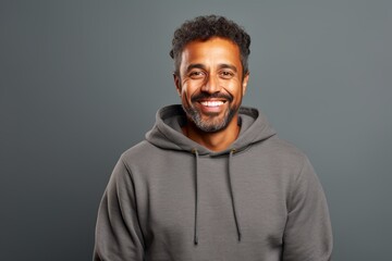 Obraz premium Portrait of a smiling indian man in his 40s sporting a comfortable hoodie in front of minimalist or empty room background
