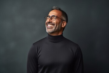 Obraz premium Portrait of a blissful indian man in his 40s wearing a classic turtleneck sweater isolated on minimalist or empty room background