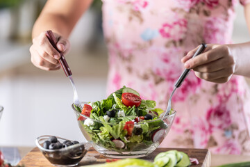 Female hands mixing a healthy spring salad made from various ingredients. Concept of healthy lifestyle