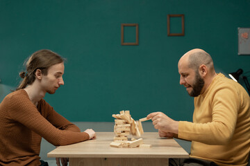 Two men playing wooden block game at home