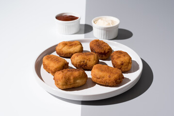 Plato de croquetas fritas con salsa de tomate y mayonesa aperitivo sobre fondo gris	