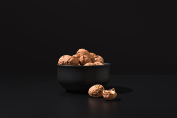 Nueces doradas en un recipiente negro sobre fondo negro