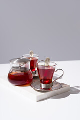 Dos tazas de té rojo y tetera sobre mármol y fondo gris	