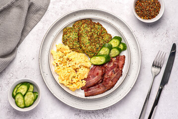 Food photography of breakfast; scrambled egg; fried; crispy; bacon, zucchini,  courgette pancake, cucumber; seasoning, brunch