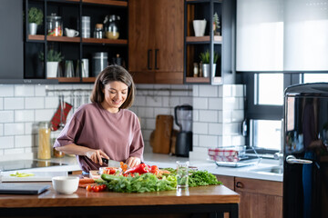 A young pretty cheerful woman is preparing a healthy various vegetable-based meal at home