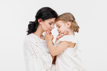 Family relationships between mother and daughter. Sensual mother with her little daughter on a light studio background. Tender moment, family support.