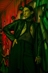 A woman stands in front of a vibrant wall covered in graffiti